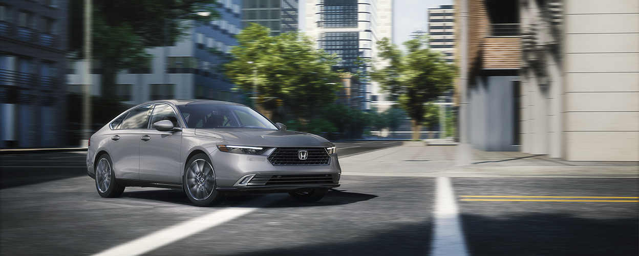 3/4 front view of grey Accord making a turn on a city street.