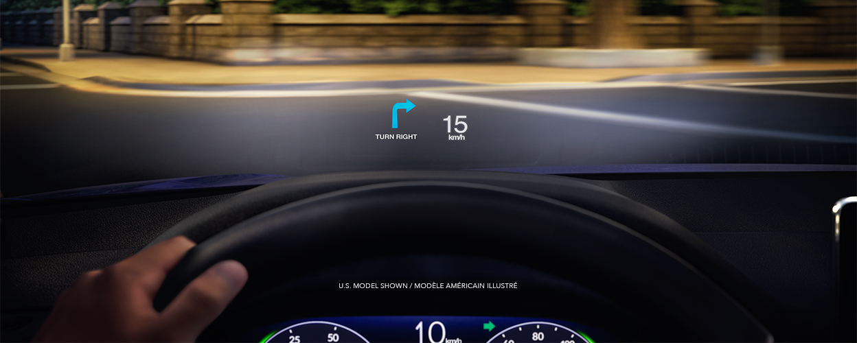 Driver's point of view. A projection on the windshield displays speed and a turn signal as the driver prepares to take a turn in a quiet city street at night. 