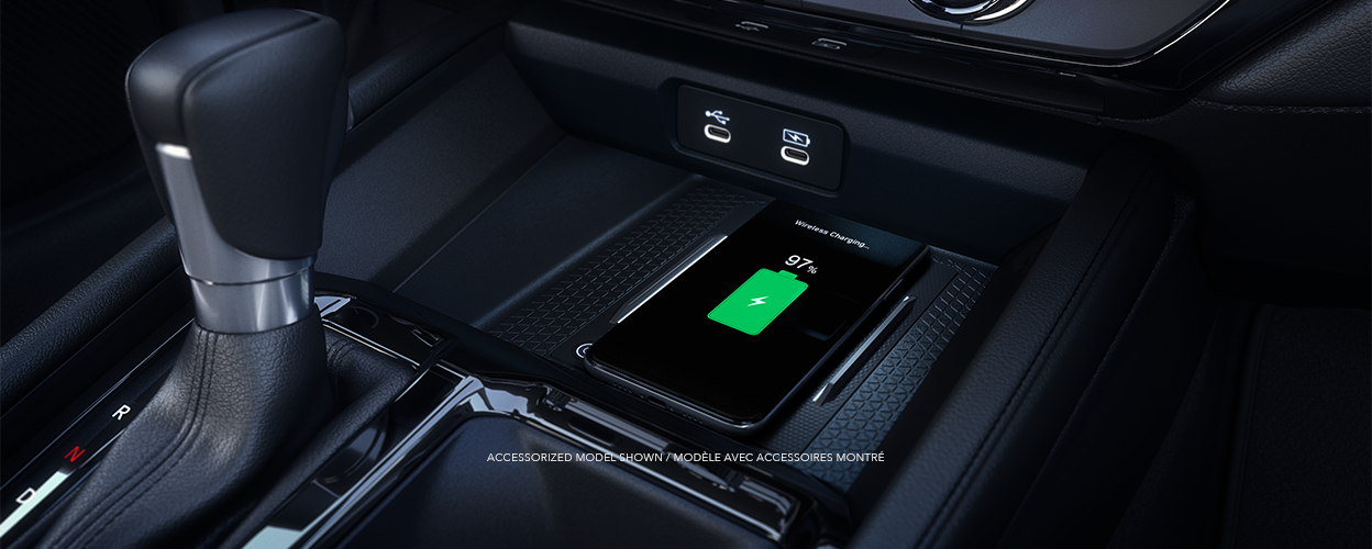 Closeup view of a compatible smartphone charging wirelessly on the charging pad in front of the gear shifter.