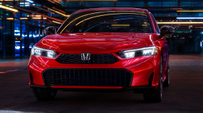 Front view of a parked blue Civic Sedan in a dark warehouse-like space.