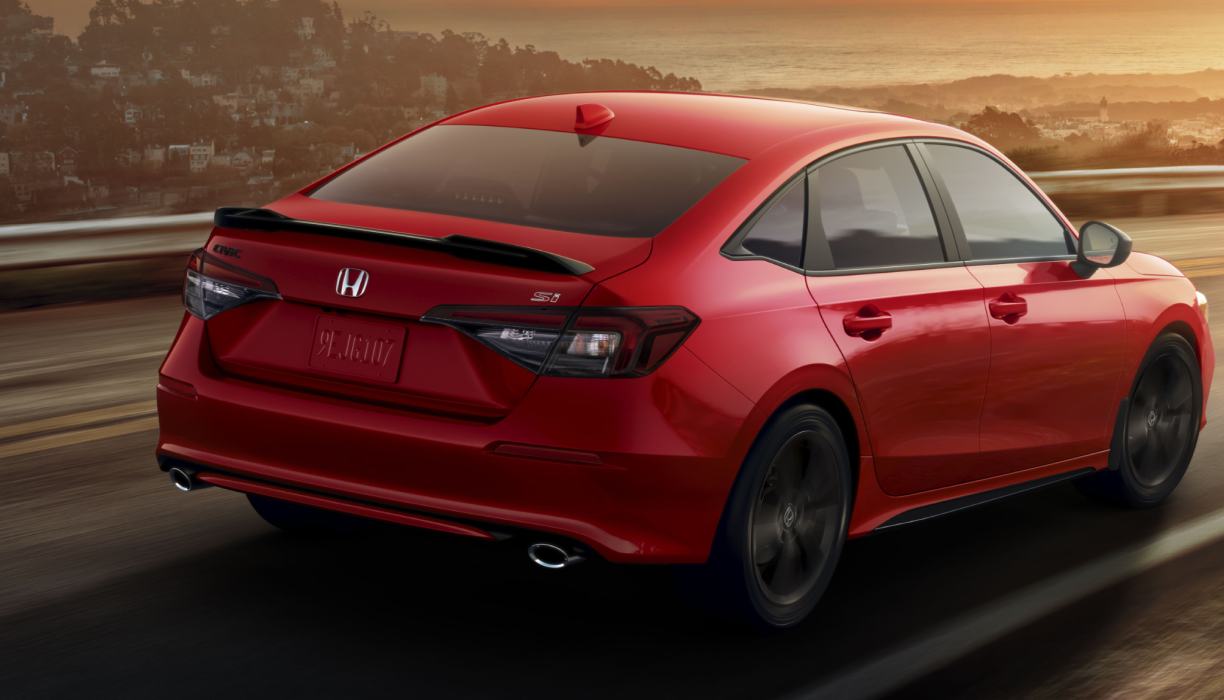 3/4 rear closeup of red Civic Si driving on highway, showcasing the rear spoiler.