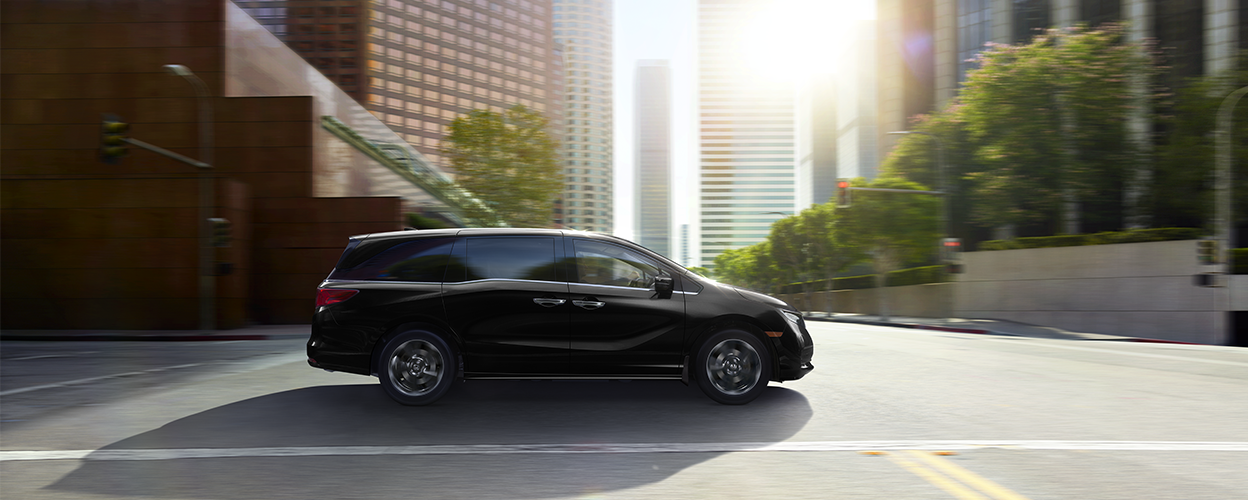 Sideview of black Odyssey driving on city street.