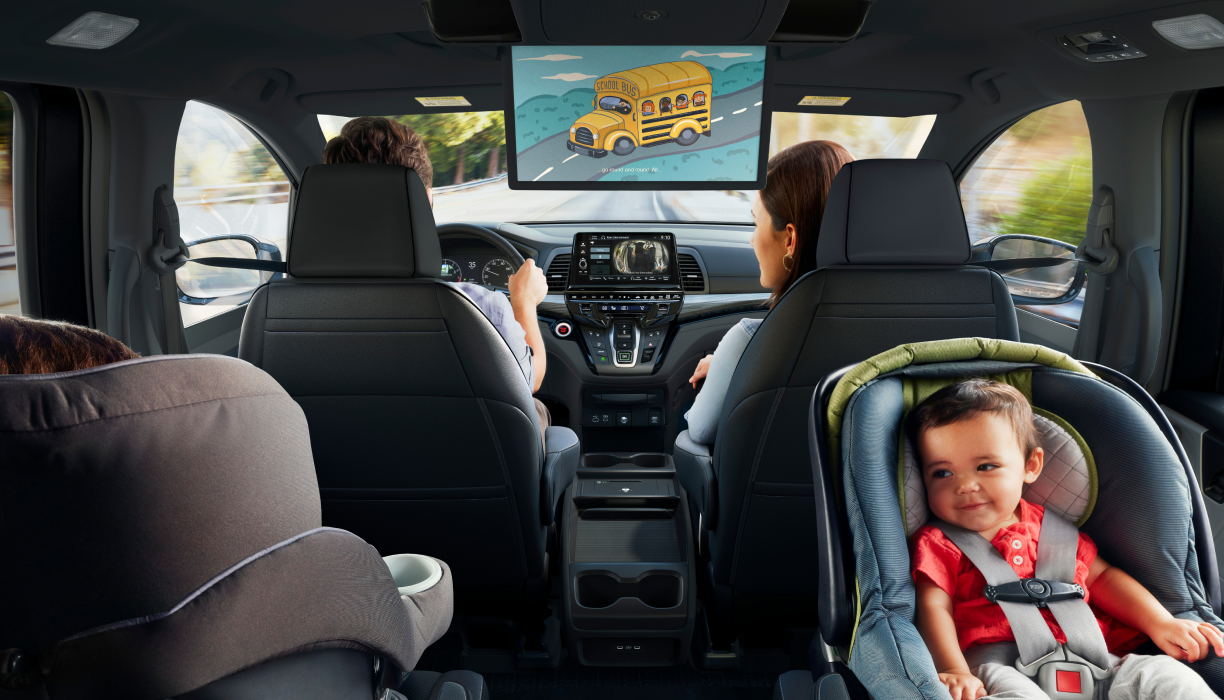 Interior view of Odyssey. Dad driving; Mom in front passenger seat; kid in car seat.