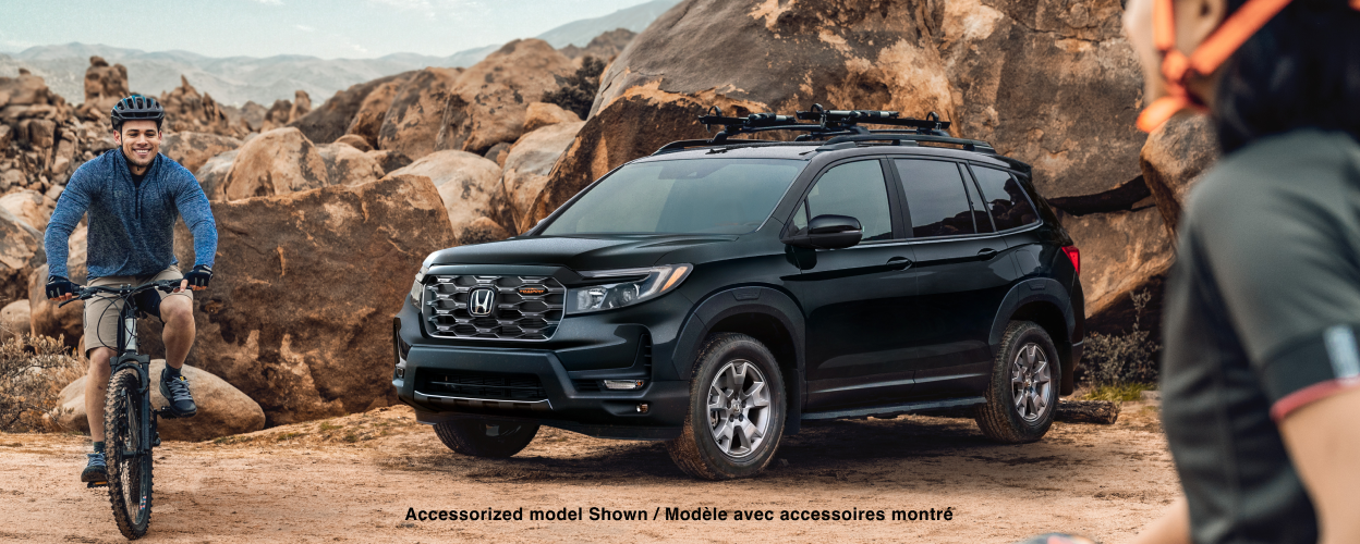 3/4 side front view of black Passport parked in desert; two mountain biking friends near it.