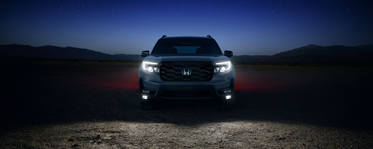 Head-on view of Passport in desert at night with headlights on.