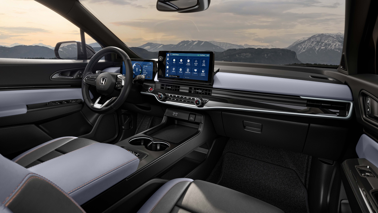 3/4 panoramic interior view of dashboard and new centre console. Out the windshield we see snowy mountaintops. 