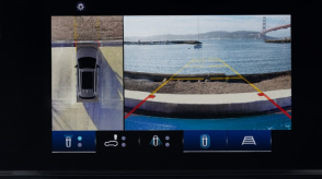 Closeup of touchscreen displaying a bird’s eye view of a Prologue in a parking spot and what the front cameras see: the curb in front, the ocean, and the Golden Gate Bridge.