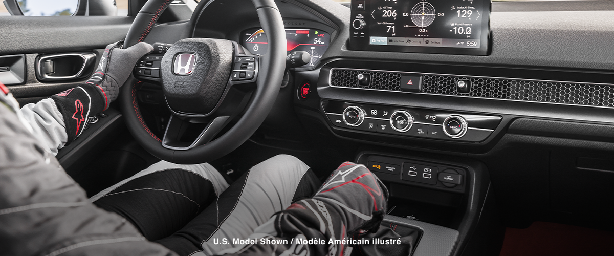 Interior view of race car driver holding wheel, showcasing the Type R interior and LogR™ info on the touchscreen display.
